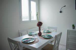 a white table with plates and a vase with flowers on it at VILLA ATHINA in Paleokastritsa +37 photos