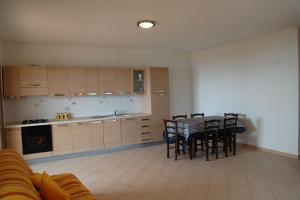 a kitchen with a table and chairs in a room at Nuovissimo appartamento con veranda vista mare a Maladroxia C63 in Maladroscia