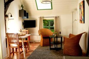 een woonkamer met stoelen en een tafel en een televisie bij De Corylus Vakantie Appartement in Oosterhesselen
