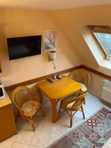 um quarto com uma mesa e cadeiras e uma televisão em Lakeside Apartman Hévíz em Hévíz