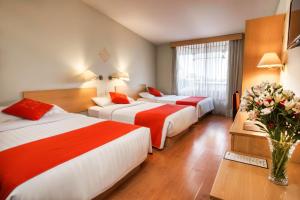 a hotel room with two beds and a vase of flowers at Lake Titicaca Hotel in Puno