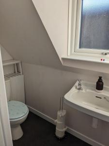 a bathroom with a toilet and a sink and a window at Craigmile Cottage in Fraserburgh