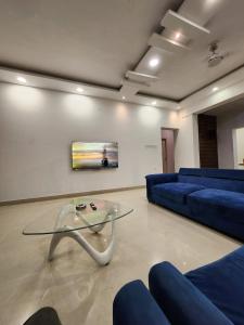 een woonkamer met een blauwe bank en een glazen tafel bij Oni Casa in Pune