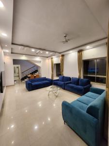 a large living room with blue couches and a table at Oni Casa in Pune