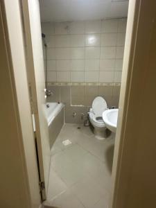 a bathroom with a toilet and a tub and a sink at Reflections Ajman-Home Away Home-Best property for stay in Ajman  +5 photos