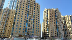 two tall buildings with cars parked in a parking lot at Reflections Ajman-Home Away Home-Best property for stay in Ajman 