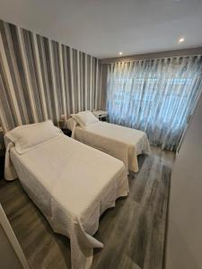 2 camas en una habitación de hotel con ventana en HOSTAL FONCALADA en Oviedo