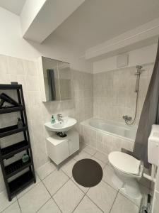 a bathroom with a sink and a toilet and a tub at urbanstays Linz Denkstraße in Linz
