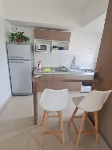 a kitchen with a white refrigerator and two white chairs at Departamento céntrico in Salta