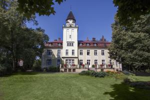 un grand bâtiment blanc avec une tour d'horloge en haut dans l'établissement Pałac Nieznanice Zabytek Gościnny ze SPA, à Nieznanice