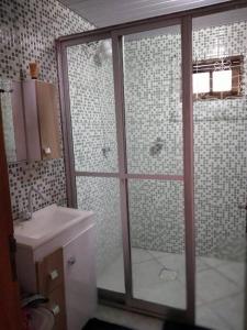 y baño con ducha acristalada y lavamanos. en Casa c/Piscina em Arroio do Rosa en Imbituba