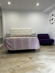um quarto com uma cama e um sofá roxo em Estudio Conil Playa em Conil de la Frontera