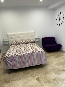 um quarto com uma cama e um relógio na parede em Estudio Conil Playa em Conil de la Frontera