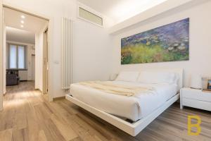 a white bedroom with a large bed and a painting on the wall at BePlace Apartments in Gioia in Milan
