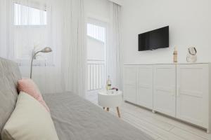 una camera bianca con un letto e una TV a parete di Apartament Mewa a Dziwnówek