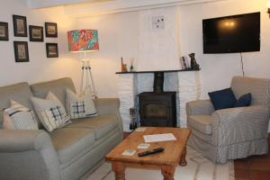 a living room with two couches and a fireplace at Ginentonic Holiday Cottage in Saint Keverne