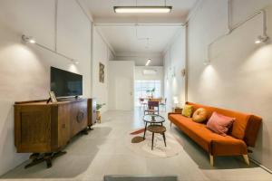 a living room with an orange couch and a television at Sukhumvit entire house 7 pax - 2 mins walk from skytrain in Bangkok