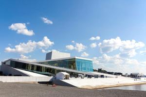 a large glass building with people walking in front of it at Koselig leilighet i sentrum av OSLO med byutsikt! in Oslo