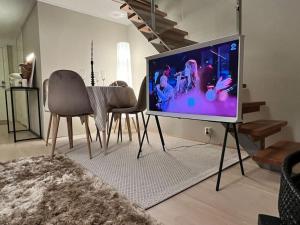 Una sala de estar con televisión, mesa y sillas. en Koselig leilighet i sentrum av OSLO med byutsikt!, en Oslo
