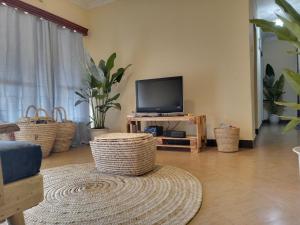 sala de estar con TV y sillas de mimbre en Arusha-paradise-home, en Nkoanrua