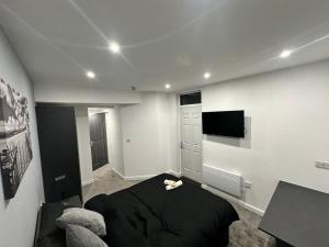 a bedroom with a black bed and a flat screen tv at Luxurious 2 bedroom flat in Beeston Hill