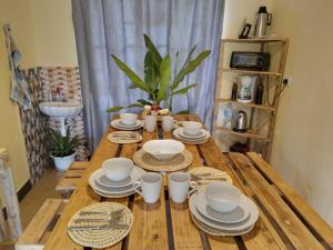 una mesa de madera con tazas y platos. en Arusha-paradise-home, en Nkoanrua