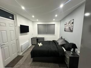 ein Schlafzimmer mit einem schwarzen Bett und einem TV in der Unterkunft Luxurious 2 bedroom flat in Beeston Hill