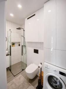 a white bathroom with a shower and a washing machine at Apartament White in Giżycko