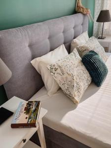 a bed with pillows and a book on a table at Apartament White in Giżycko