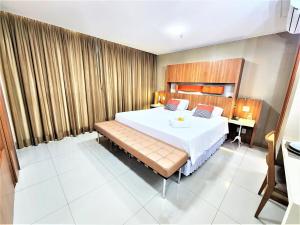 Un dormitorio con una cama grande y un banco. en Bloco A AP 310 · Hotel Jade, Park Sul vista livre en Brasilia