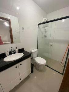 a bathroom with a sink and a toilet and a shower at Casa pertinho da praia doTombo in Guarujá +4 photos