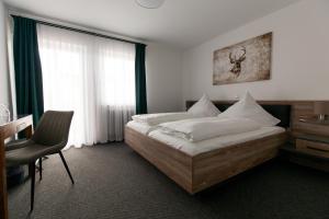 a bedroom with a bed and a desk and a window at Landgasthof Schützen in Tengen