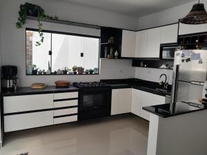 a kitchen with white cabinets and black appliances at Casa pertinho da praia doTombo in Guarujá
