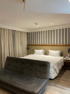 a bedroom with a large bed and a couch at Suite Radisson Vila Olimpia in Sao Paulo