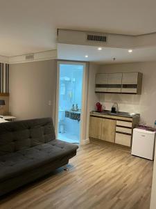 a living room with a couch and a kitchen at Suite Radisson Vila Olimpia in Sao Paulo