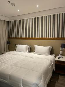 a large white bed in a room with a desk at Suite Radisson Vila Olimpia in Sao Paulo