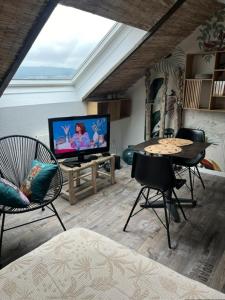 a living room with a tv and a table and chairs at LE BALI in Besançon