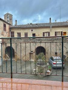 a fence with cars parked in front of a building at La casina nel convento in Asciano