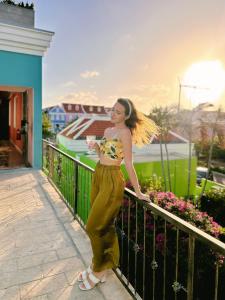 a woman standing on a fence with a drink at BOHO Bohemian Boutique Hotel in Willemstad