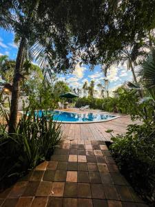 einen Pool in einem Resort mit Palmen in der Unterkunft Vila Cizinho in Itaúnas