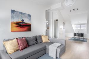 a living room with a gray couch and a painting on the wall at Citykoti Downtown Studios in Helsinki