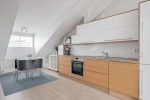 a kitchen with white cabinets and a sink and a table at Citykoti X 2ndhomes Downtown Studios in Helsinki