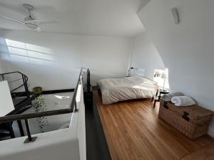 een slaapkamer met een bed in een kamer met houten vloeren bij Duplex apartment with terrace and closed parking - Stade Charléty Paris in Arcueil
