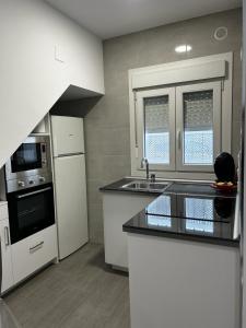a kitchen with white cabinets and a sink and appliances at Apartamento Conil Playa in Conil de la Frontera