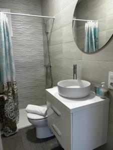 a bathroom with a sink and a mirror and a toilet at Apartamento Conil Playa in Conil de la Frontera