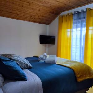 a bedroom with a large blue bed with yellow curtains at Casa das Camélias in Viseu