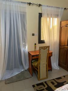 a desk and a chair in a room with curtains at Diabir in Ziguinchor