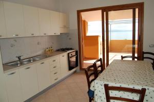 a kitchen with white cabinets and a table with a table cloth at Rifinito appartamento con veranda vista mare a Maladroxia C65 in Maladroxia