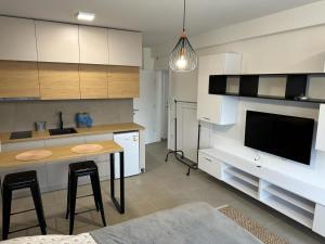 eine Küche mit weißen Schränken, einem Tisch und einem TV in der Unterkunft Apartment Niš in Niš
