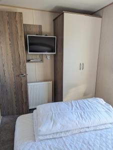 1 dormitorio con 1 cama y TV de pantalla plana en Caravan sleeps 8 at Littlesea, Weymouth, en Wyke Regis